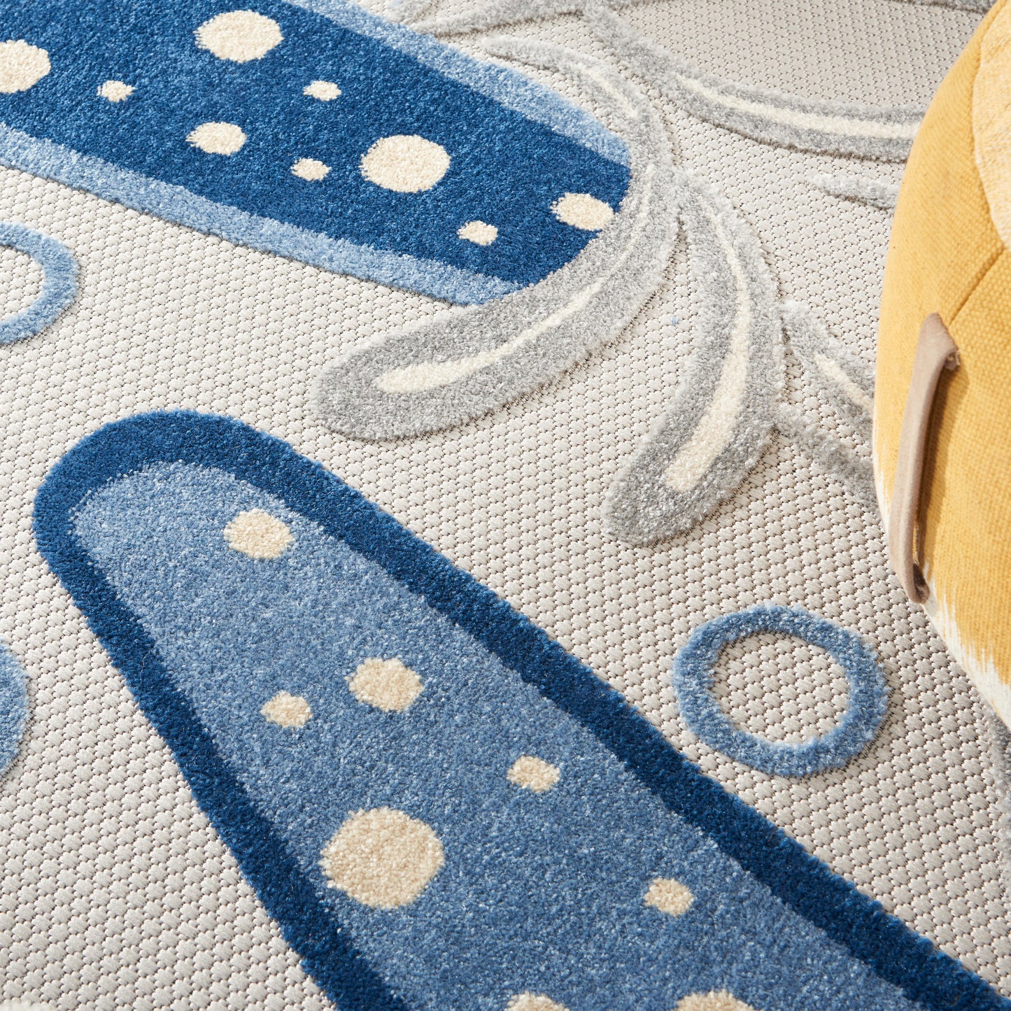 Abstract blue round rug with navy and light blue oval shapes, cream dots and gray lines on a beige background; suitable for children's room decor.