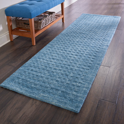 Blue textured hallway runner rug, 8' long, on dark wood floor beside a wooden bench with tufted blue cushion and wicker basket shelf.