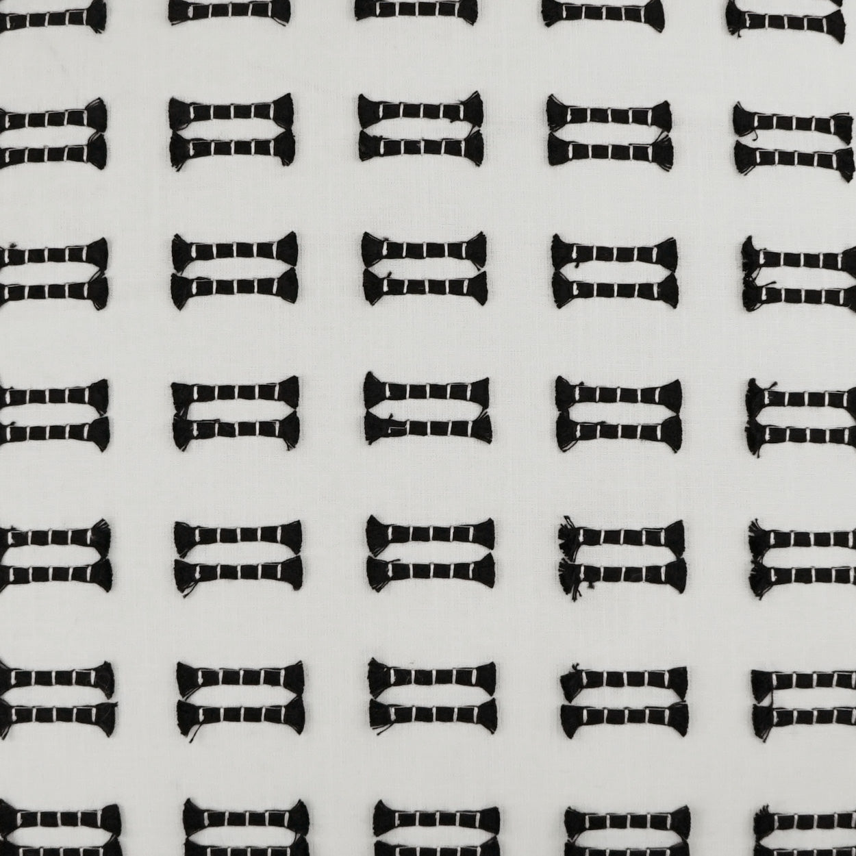 Repeating black linked-rectangle shapes on pale fabric; geometric, modern textile pattern.