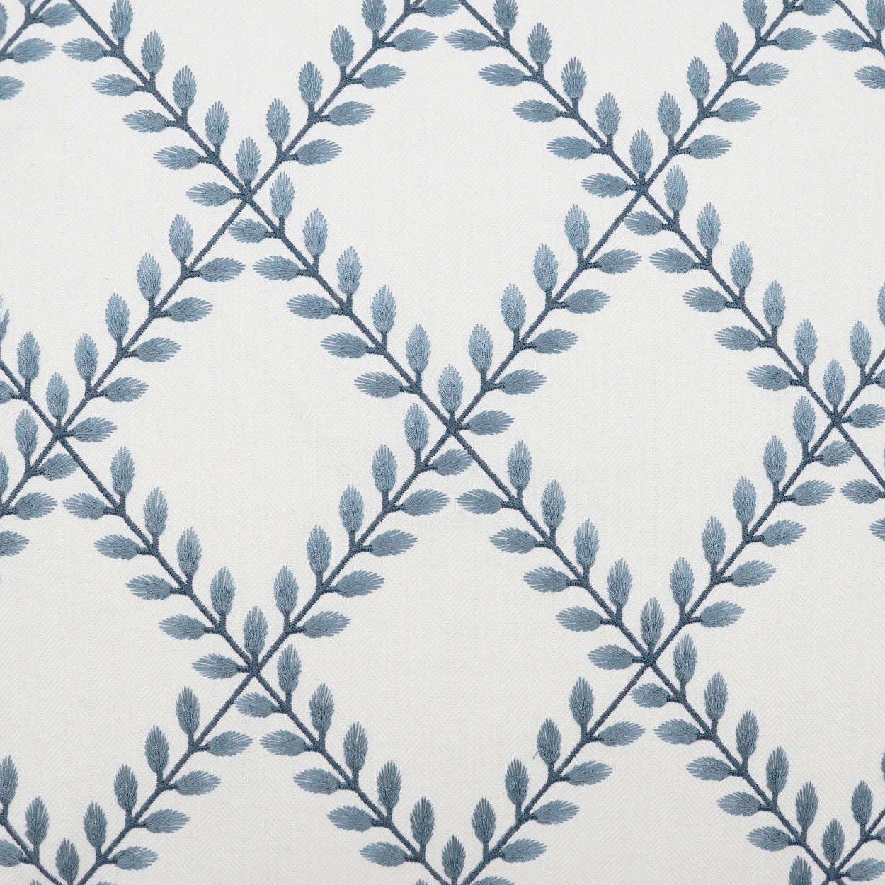 White fabric with blue-gray leafy vine pattern forming a diamond lattice & decorative textile.