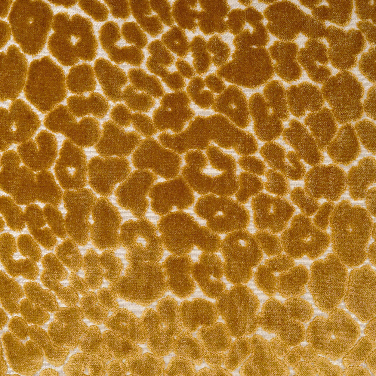 Golden brown leopard-print pillow with irregular dark spots on a tan background.