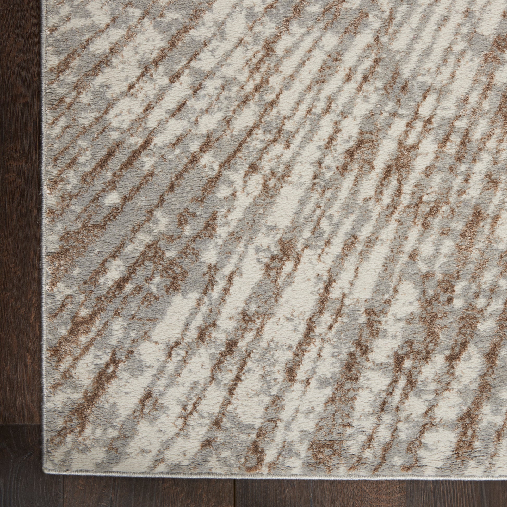 Cream and brown abstract striped rug with diagonal brushstroke pattern on dark wood floor.