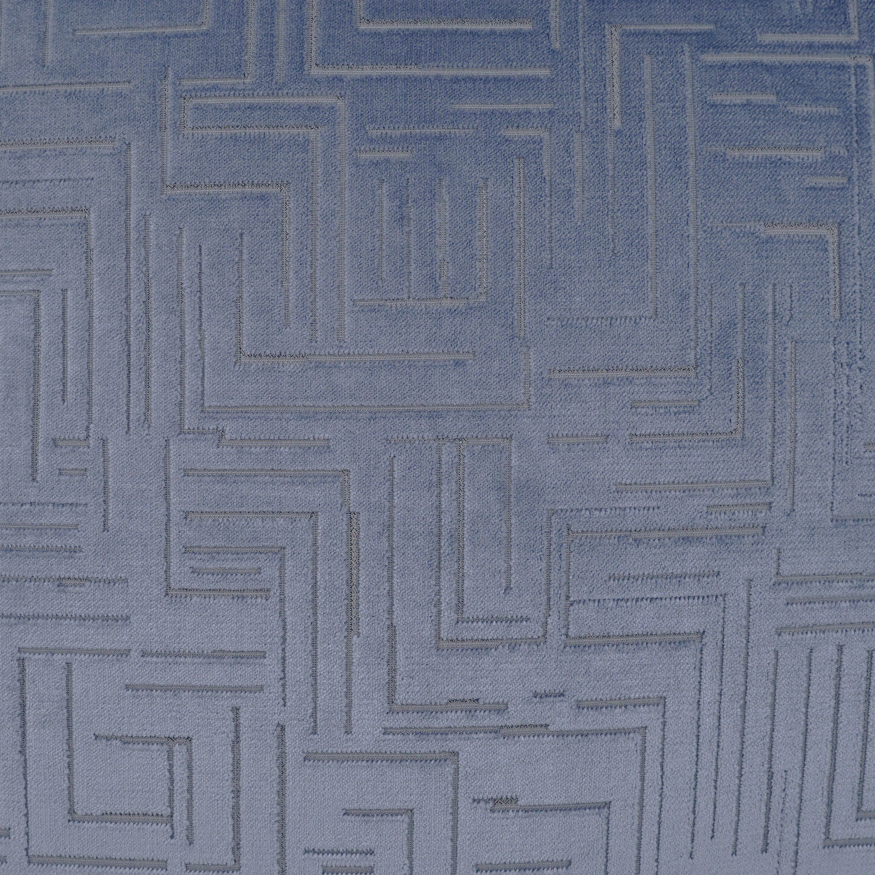 Blue fabric close-up with a raised geometric maze pattern, textured textile ideal for upholstery or home decor.