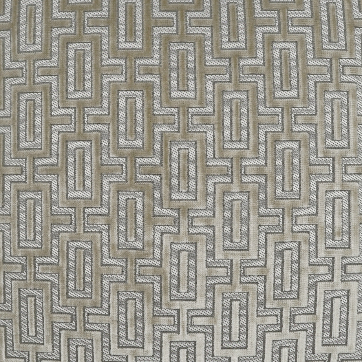 Beige-taupe woven fabric with light-gray and white interlocking rectangular geometric pattern; upholstery or cushion material.
