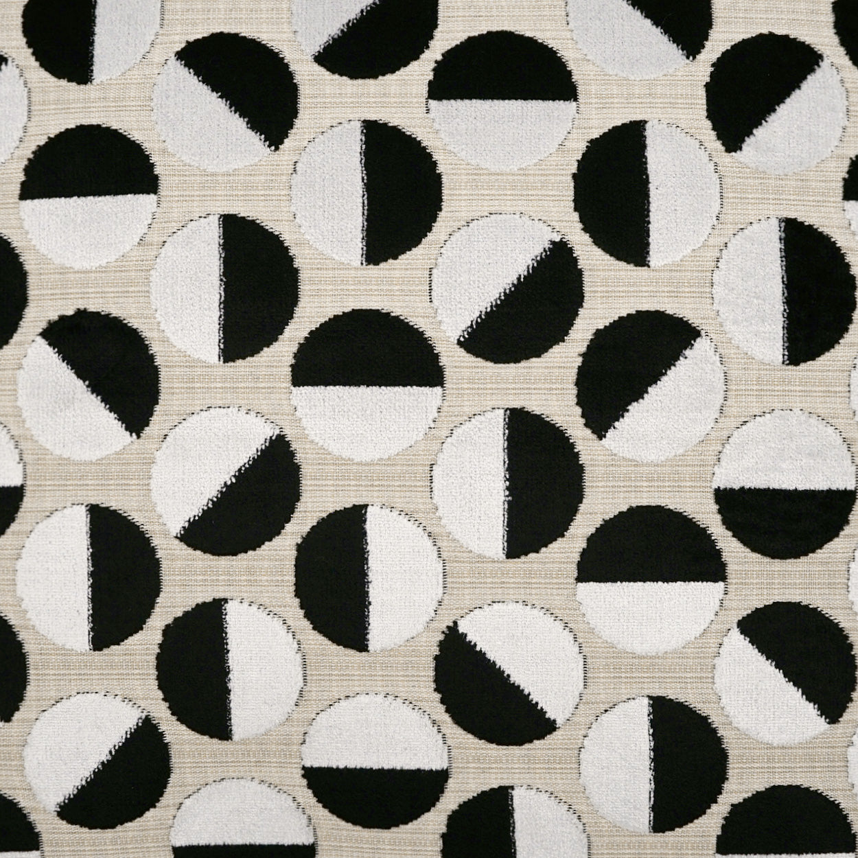 Beige woven fabric with a repeating black-and-white circle motif; each circle diagonally split into black and white halves.