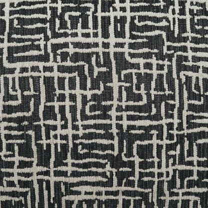 Black and white woven fabric with a geometric maze-like pattern on a 24" x 24" pillow; bold decorative textile.