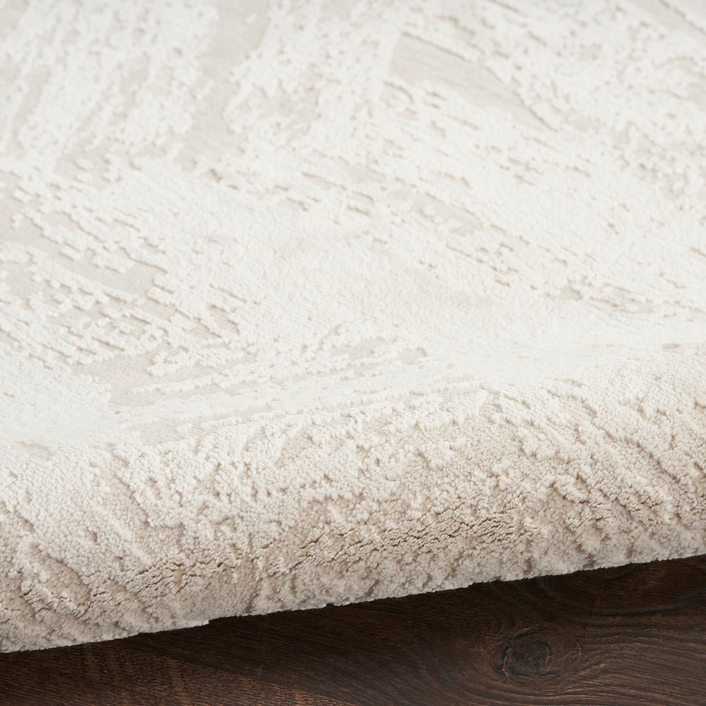 Cream plush rug with thick shag pile and subtle pattern on dark wood floor.