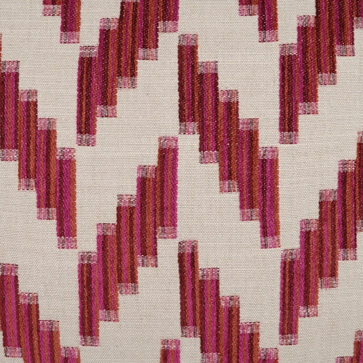 Beige woven fabric with magenta burgundy stepped chevron zigzag pattern, decorative textile for upholstery or curtains.