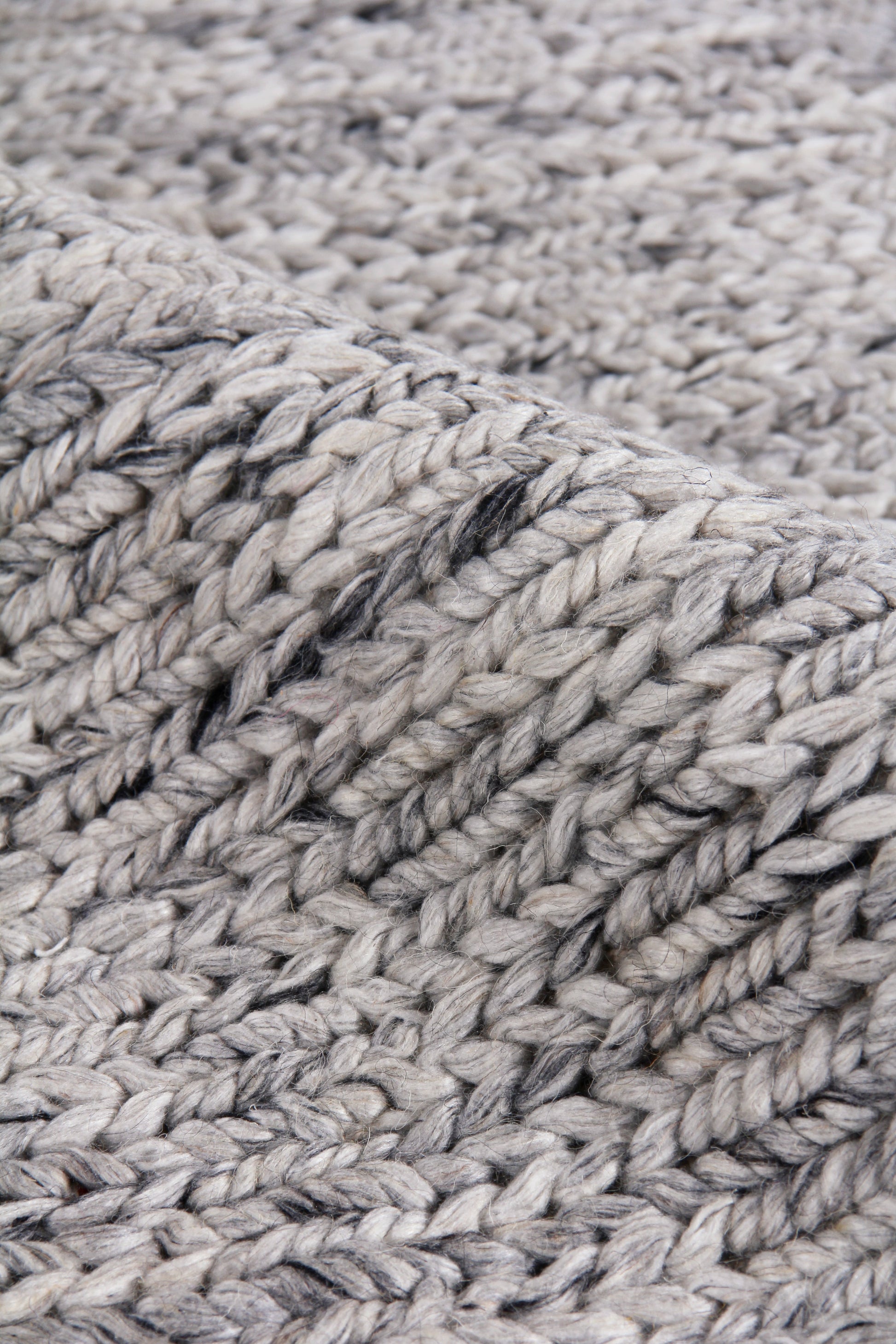 Close-up of chunky grey hand-woven rug texture with thick wool pile; textured ribbed weave, 5' x 8' indoor rug.