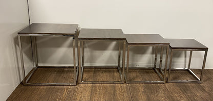 Five rectangular nesting tables with dark wood tops and metal frames, arranged in a stepped line along a wooden floor.