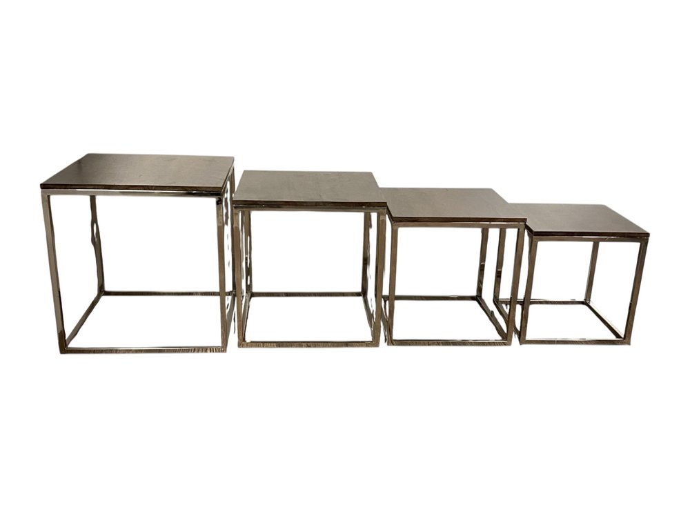 Four-piece set of industrial nesting tables with square metal frames and flat brushed steel tops.