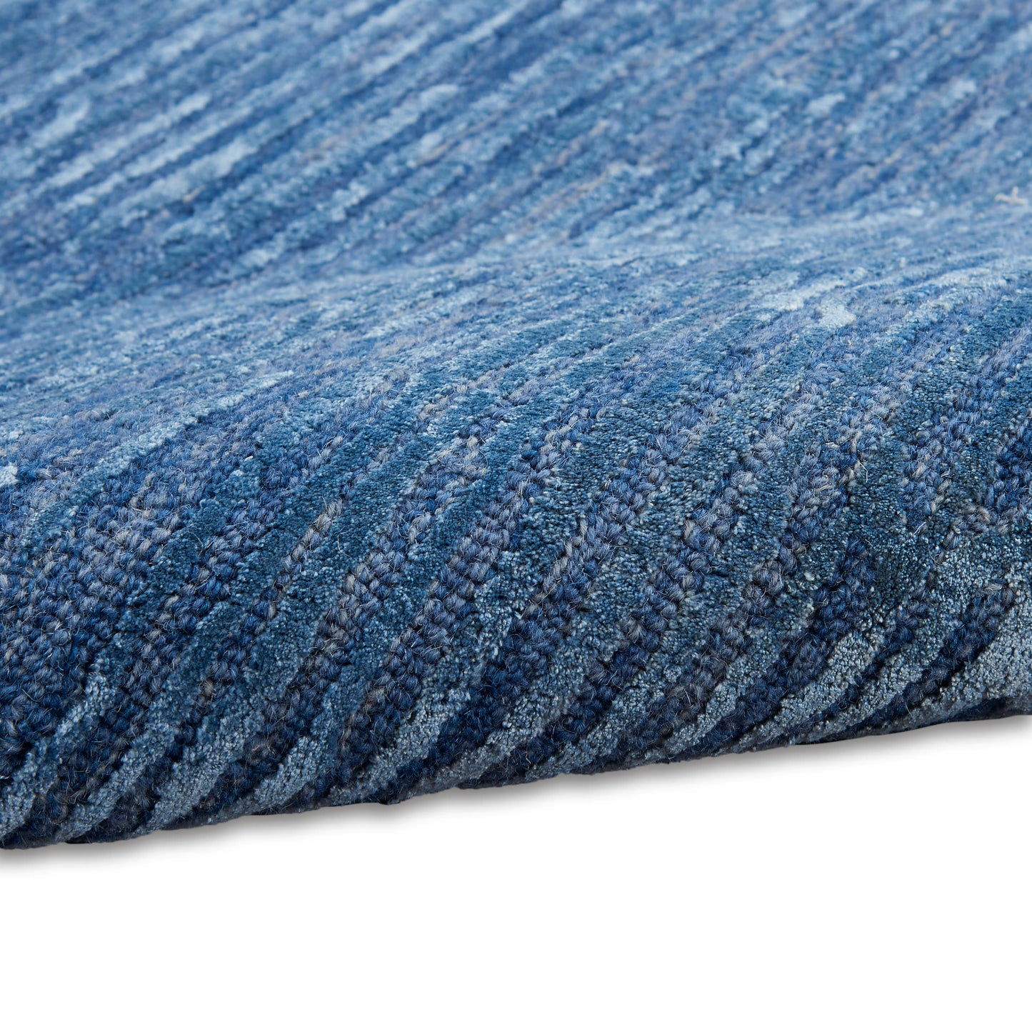 Blue textured rug close-up with looped pile in denim blues, modern woven style for living spaces.
