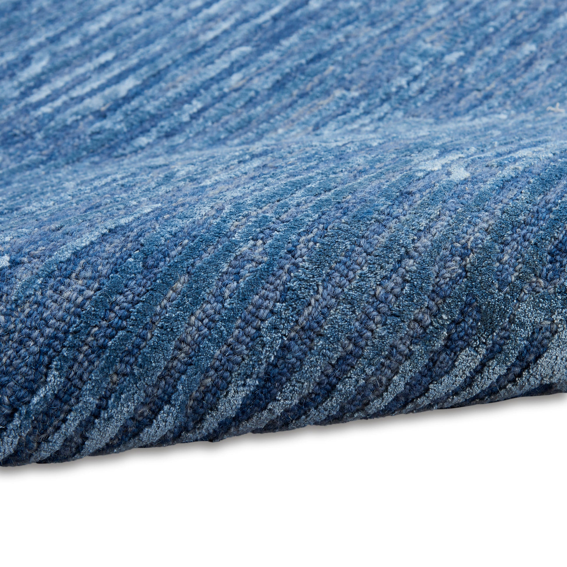 Blue textured rug close-up with looped pile in denim blues, modern woven style for living spaces.