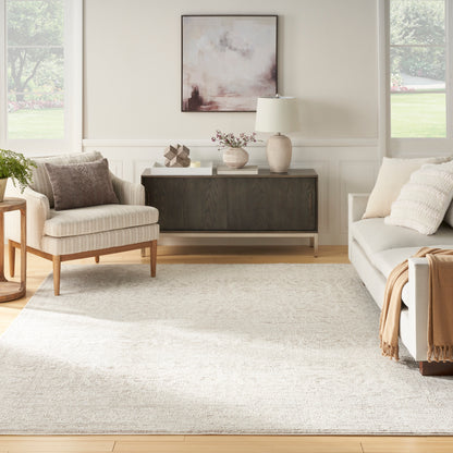 Neutral contemporary living room with beige walls, light sofa and armchair, dark wood console, beige rug, abstract art.
