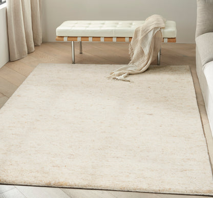 Cream plush area rug in a minimalist living room with a white tufted bench, beige throw, and light wood floor.