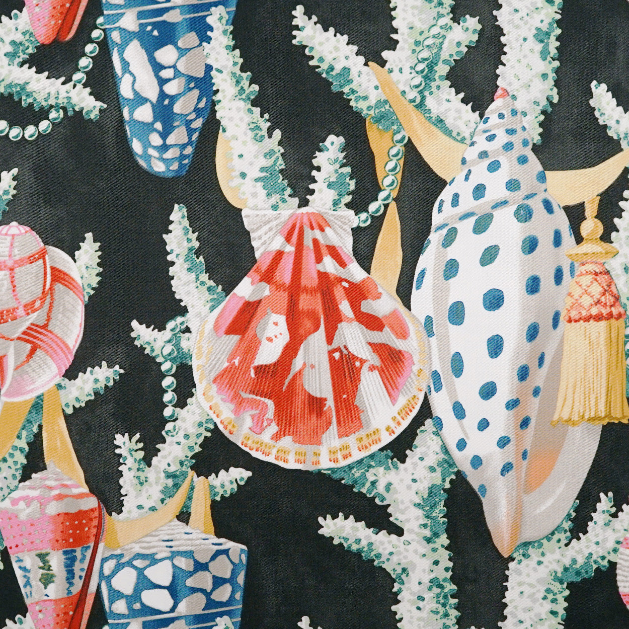 Colorful seashell and coral print fabric with blue, red and white shells on a black background.