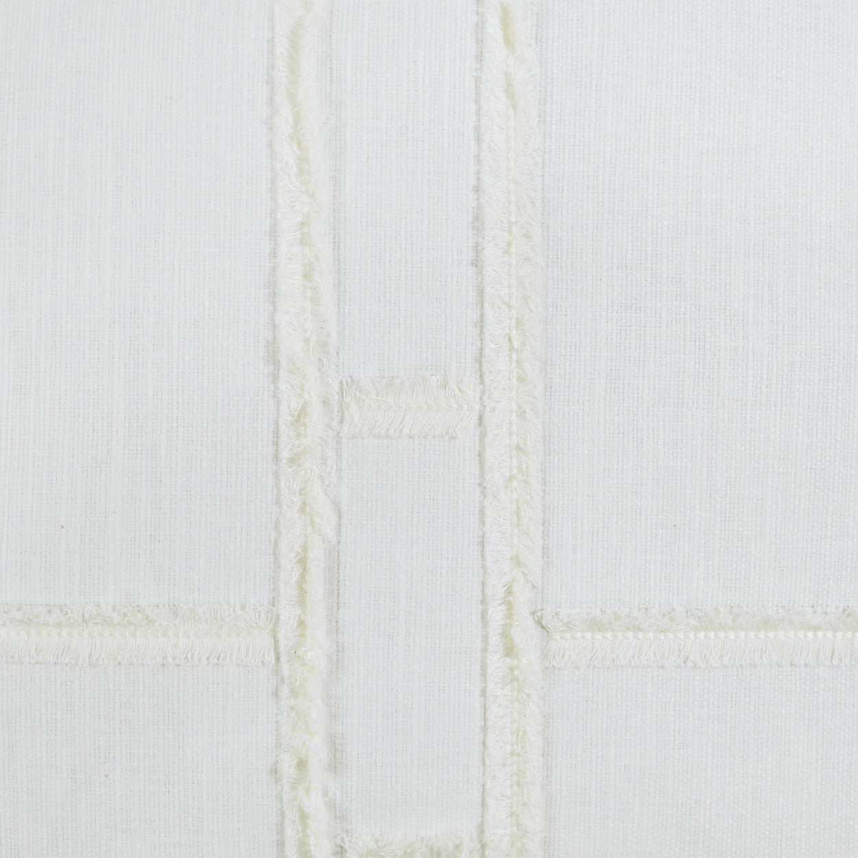 White fabric pillow with pale cream embroidered grid forming rectangular panels; soft, quilted textile look.