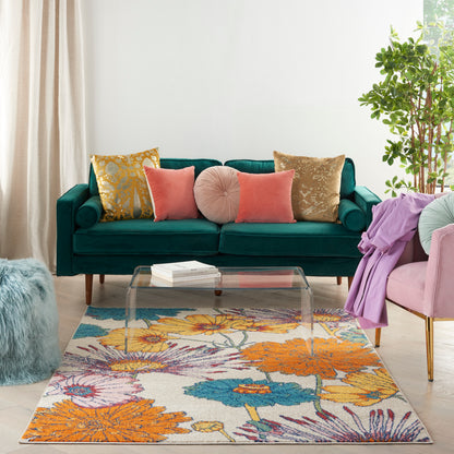 Teal velvet sofa with assorted cushions, glass coffee table, vibrant floral rug, pink chair with purple throw, potted plant.