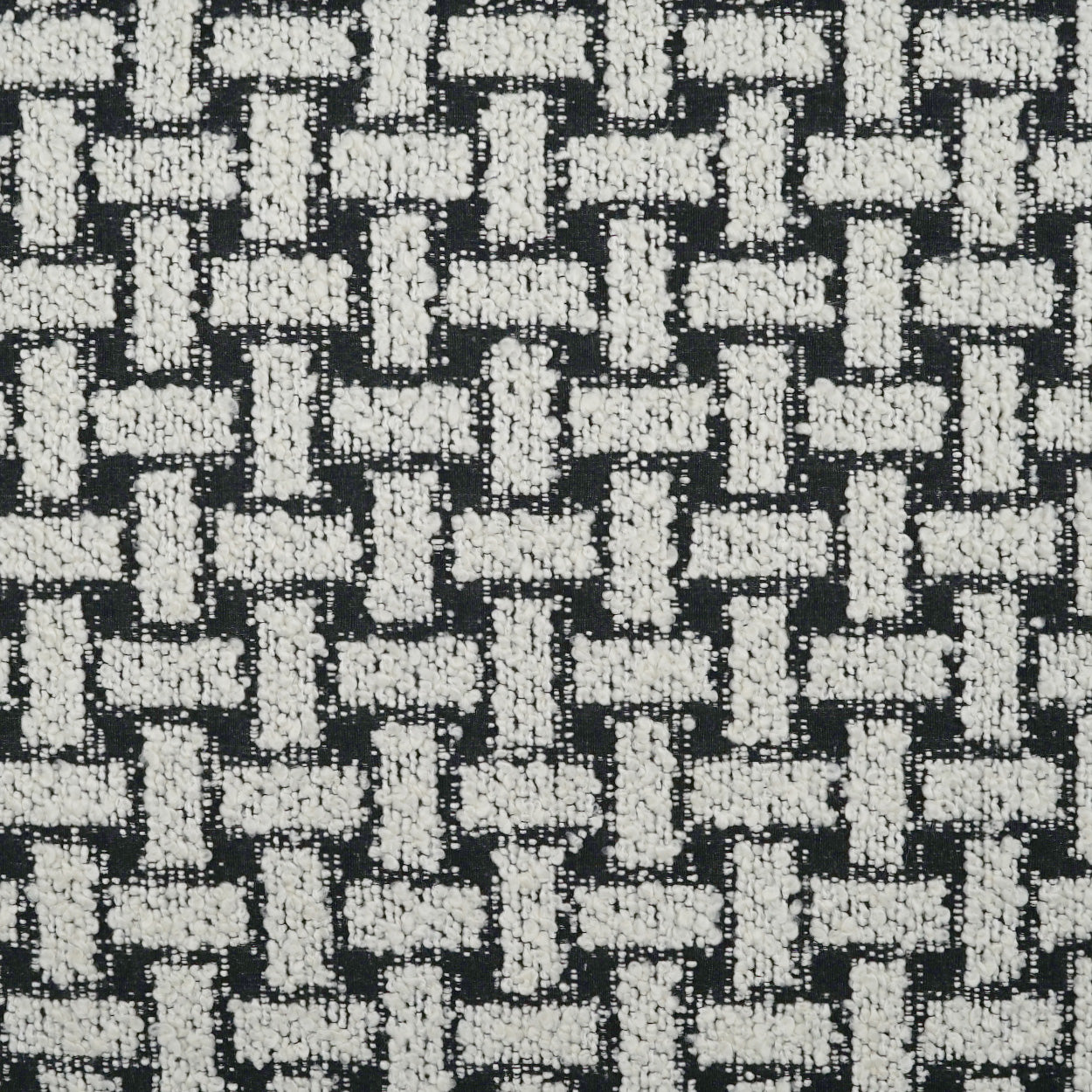 Black and white woven pillow with a basketweave texture; chunky white yarns create a bold geometric pattern.