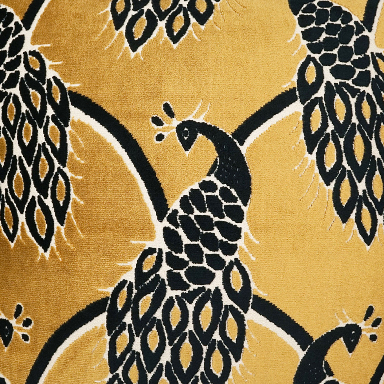 Gold fabric with bold black peacock motif & white accents; ornate botanical pattern suitable for upholstery or drapery.