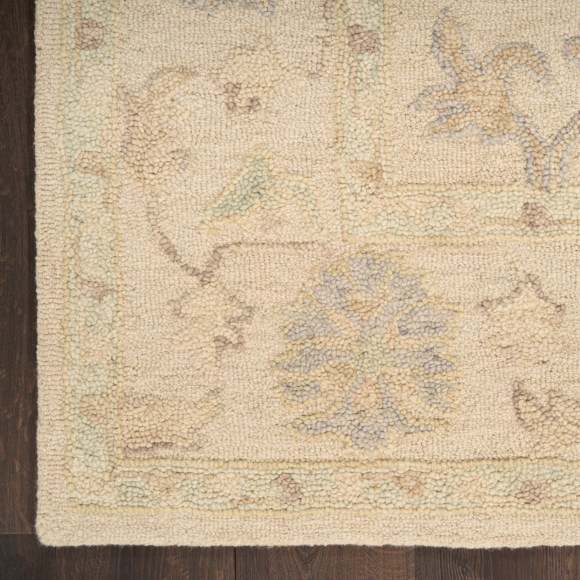 Beige oriental rug corner with pale blue floral medallion and pastel border on dark wood floor