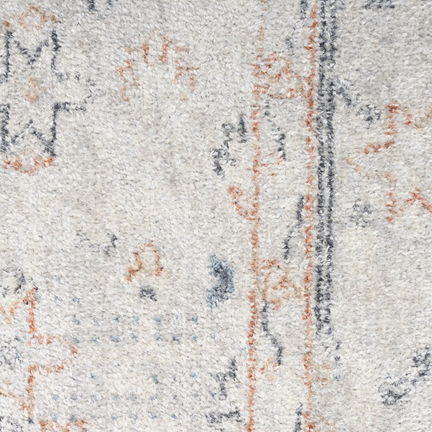 Close-up of a light beige textured rug with abstract blue-gray and rust orange motifs and a dark vertical stripe.