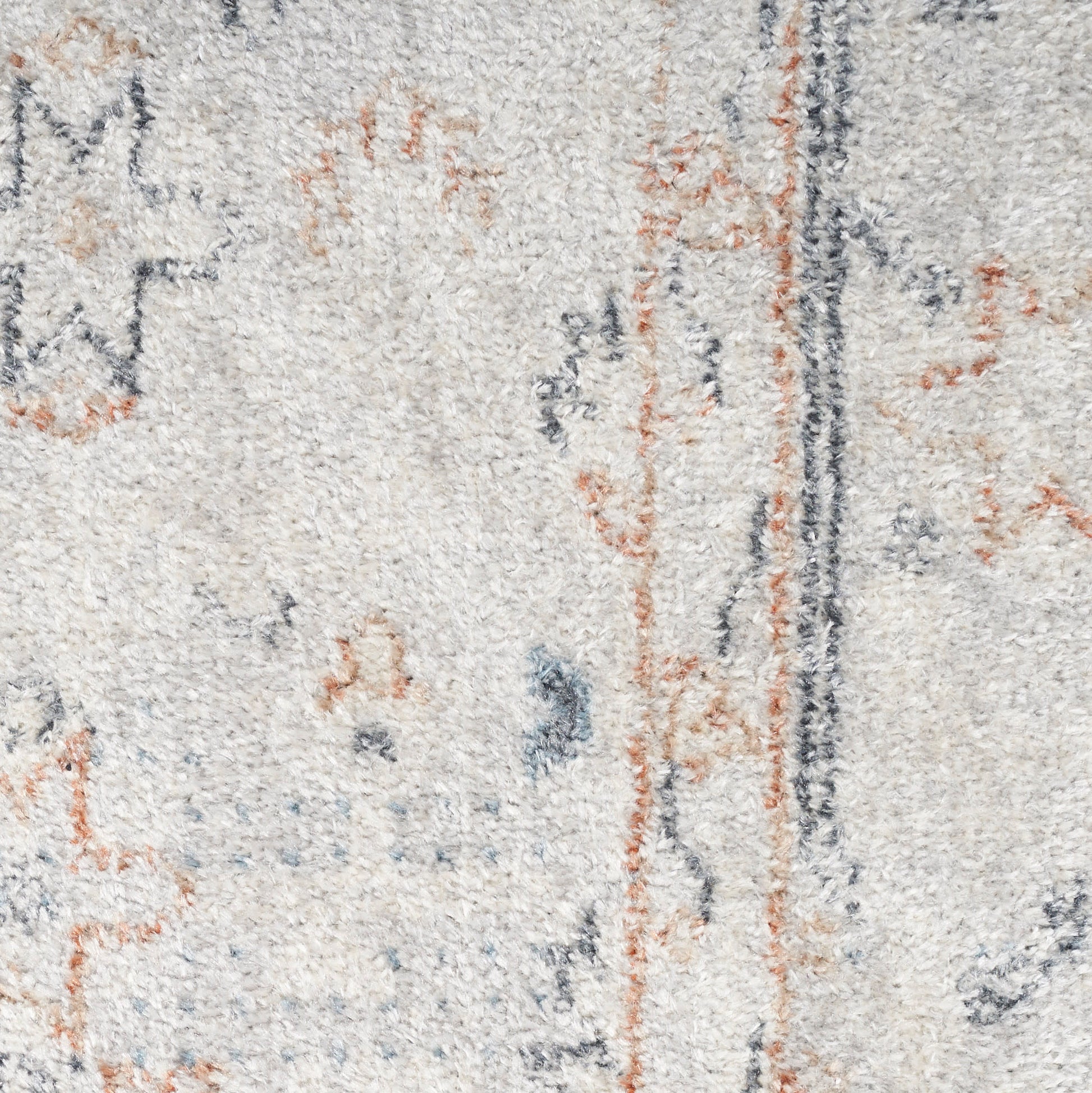 Close-up of a light beige textured rug with abstract blue-gray and rust orange motifs and a dark vertical stripe.