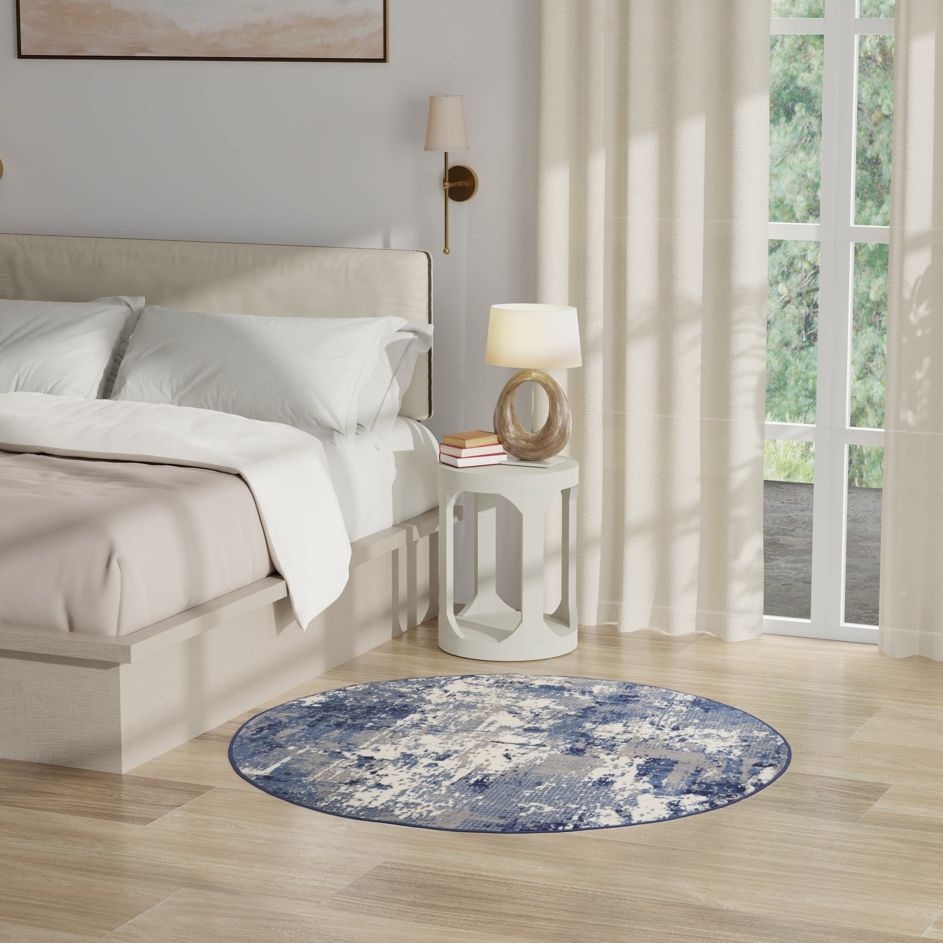 Neutral bedroom with white bedding, round blue rug, white nightstand, rope lamp, & sheer curtains by a large window.