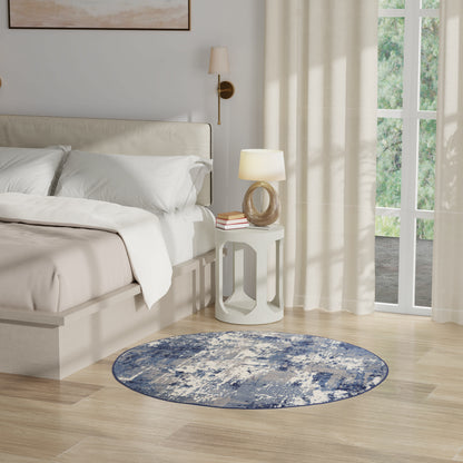Neutral bedroom with white bedding, round blue rug, white nightstand, rope lamp, & sheer curtains by a large window.