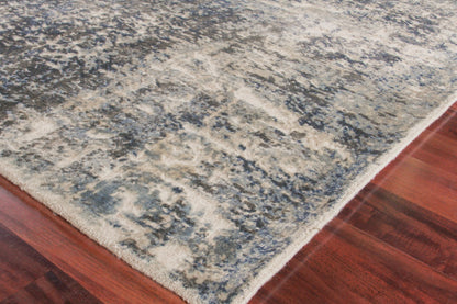 Blue-gray and ivory distressed area rug with cream border on dark hardwood floor.