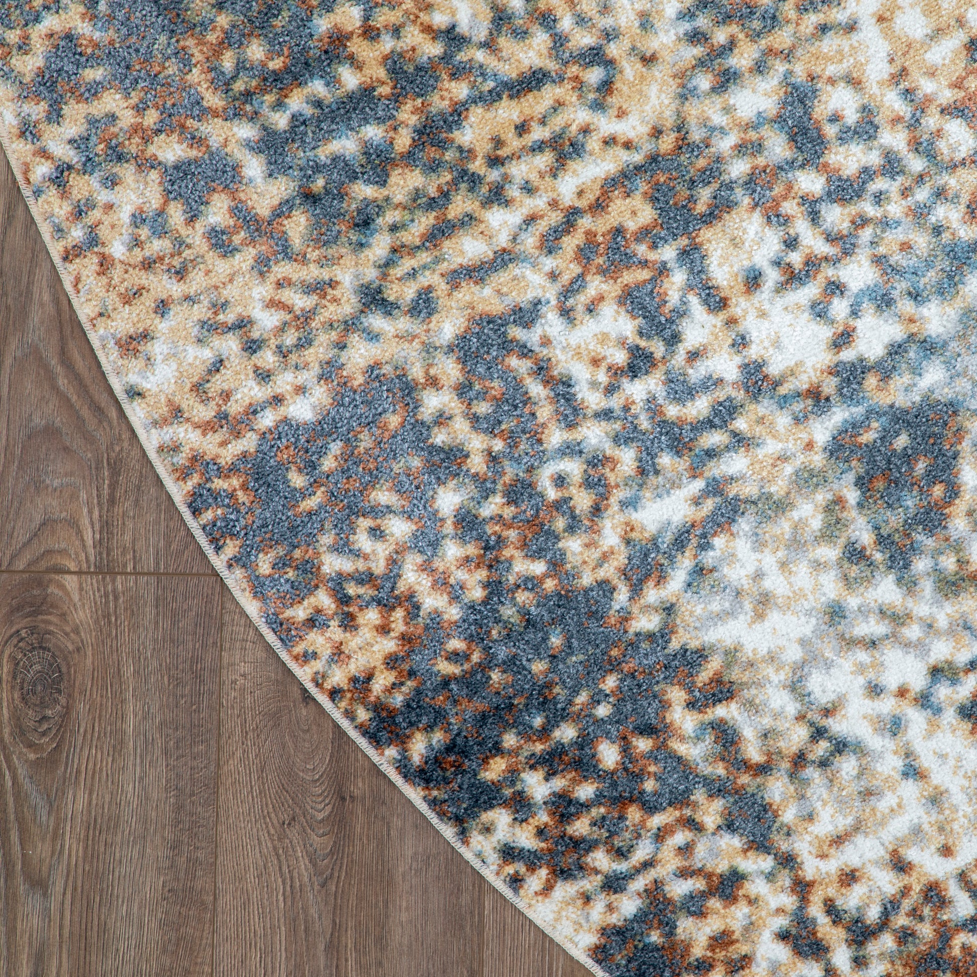 Round area rug with blue, tan and beige abstract pattern on wood floor.