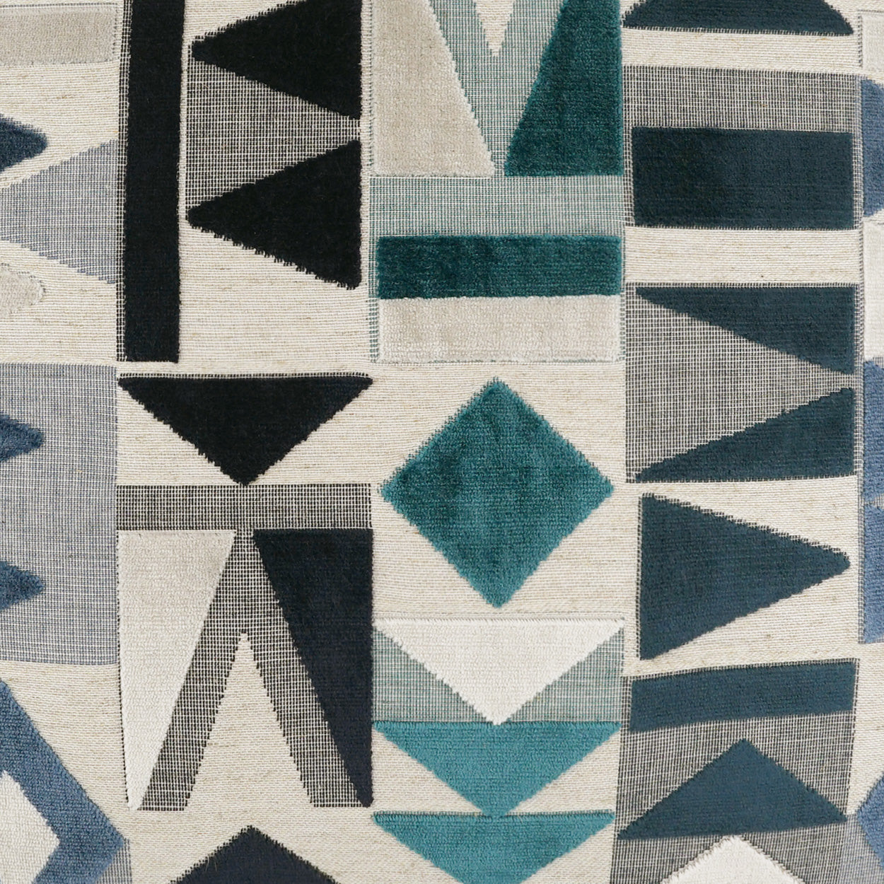 Geometric quilt-like fabric with teal, charcoal gray triangles & diamonds on a light beige background.