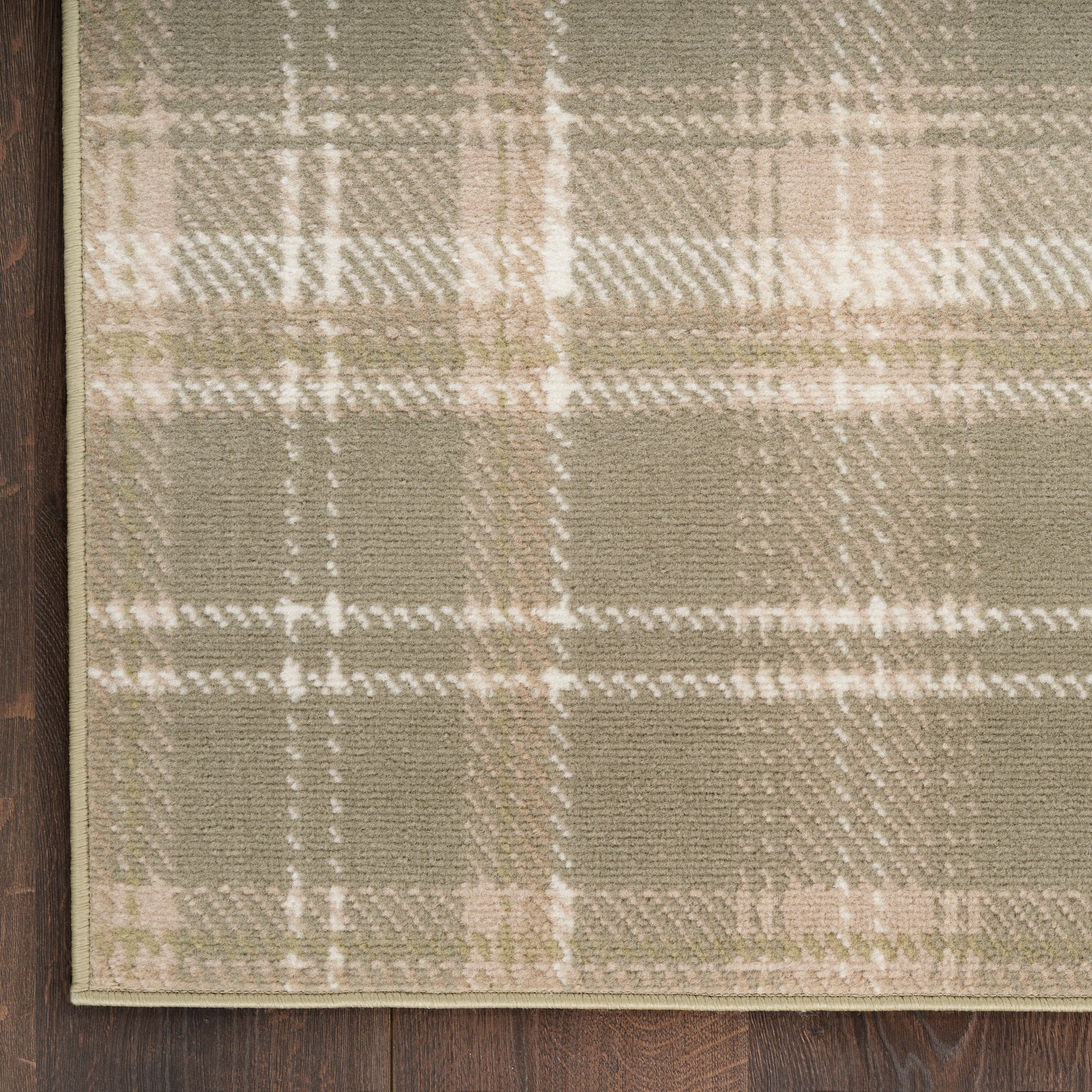Olive & beige plaid rug with cream accents on dark wood floor, woven texture.
