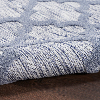 Light blue and gray geometric woven rug with braided border, rolled edge on dark wood floor.