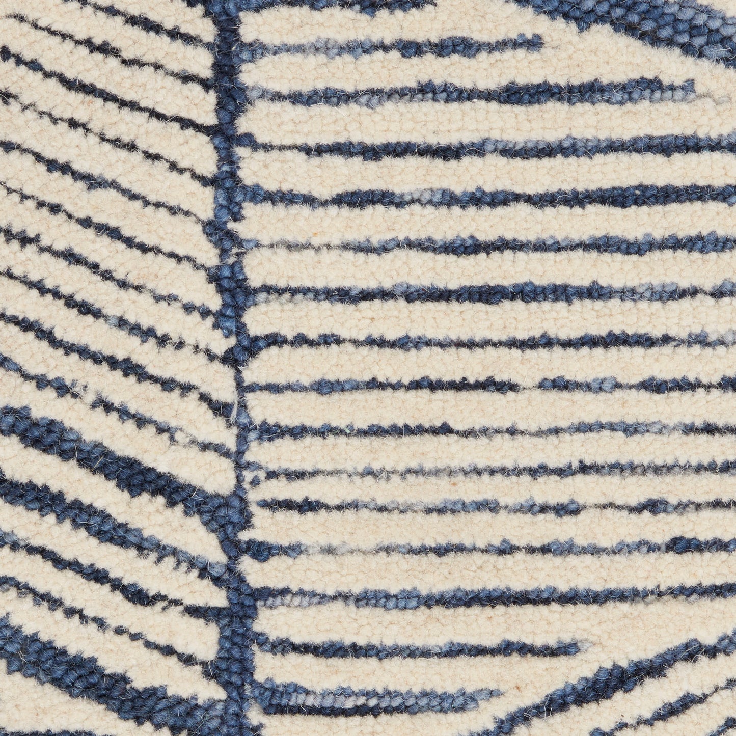 Close-up of cream textured rug with irregular navy blue stripes and looped pile.
