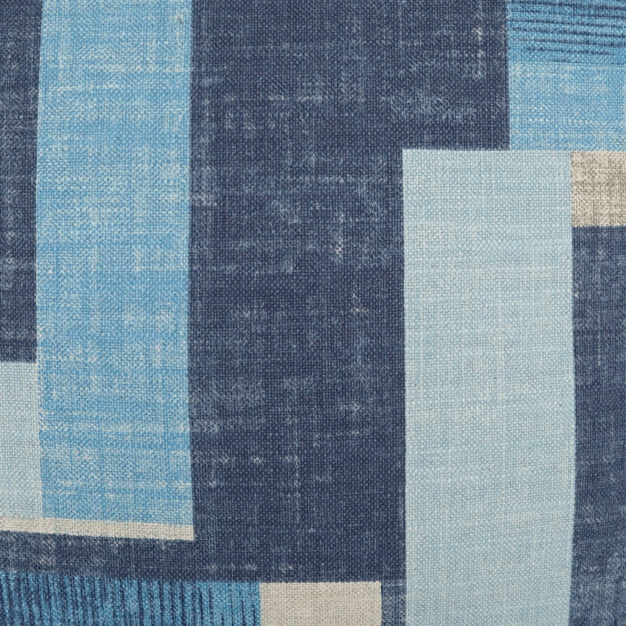 Geometric blue fabric pattern with navy, light blue and beige rectangles; textured textile for upholstery or cushions.