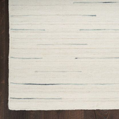 Cream flat-weave rug with subtle blue horizontal stripes on dark wooden floor.