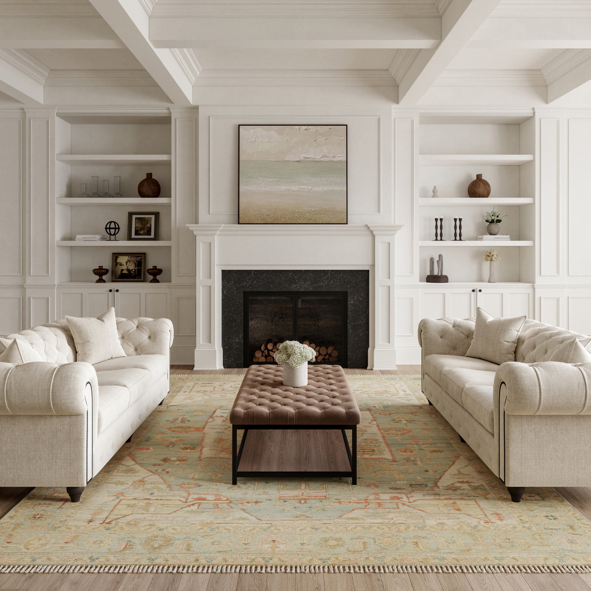 White paneled living room with fireplace, built-in shelves, beige tufted sofas, brown tufted ottoman, pastel rug.