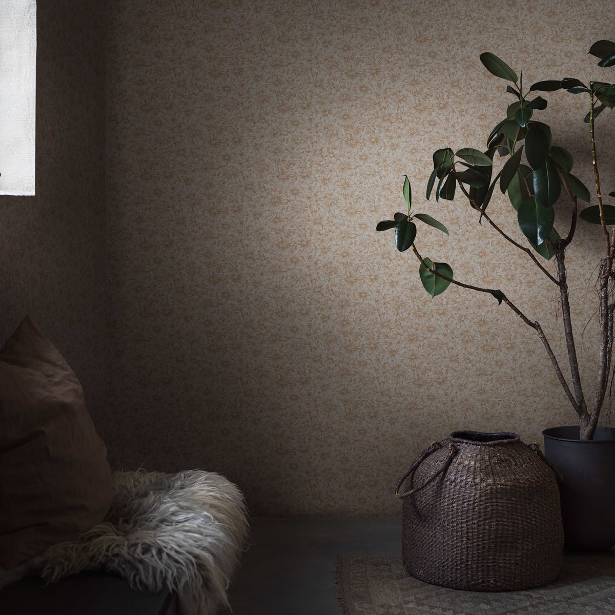 Cozy interior corner: tall plant in black pot, woven basket, shaggy white throw on brown seating, beige floral wallpaper.