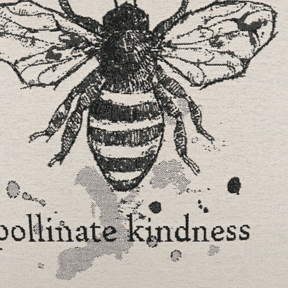 Beige linen pillow with a black bee sketch and the text 'pollinate kindness'.