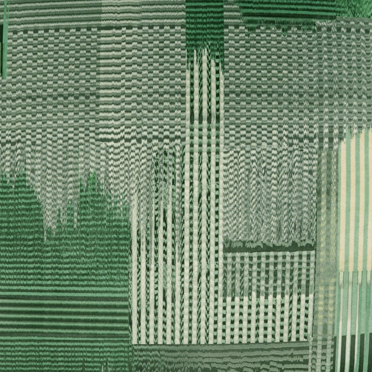 Green abstract woven fabric with geometric patchwork, stripes and checker blocks in olive to emerald tones.