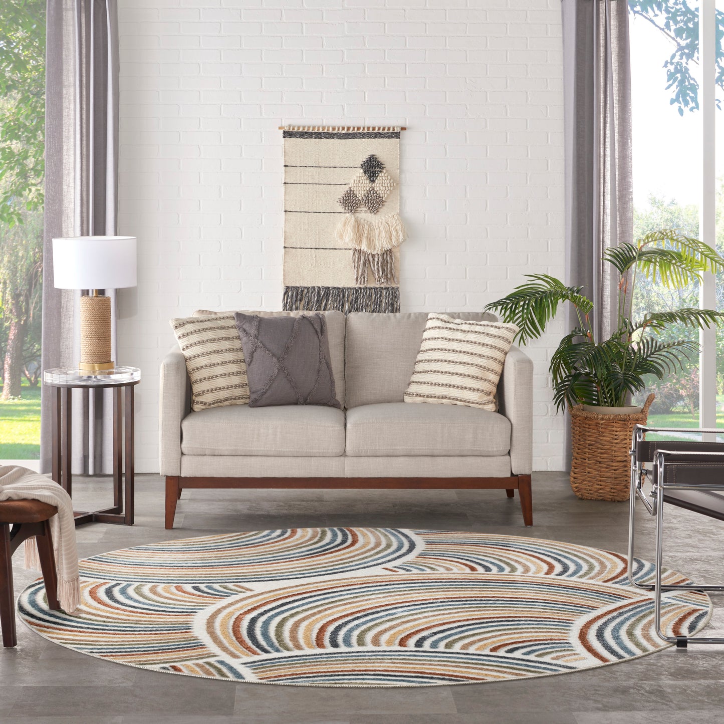 Beige mid-century sofa with striped cushions, a woven wall hanging, and a circular multicolor rug in a bright living room.