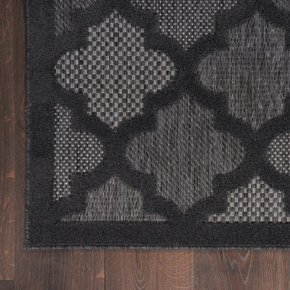 Charcoal and black flatwoven rug with bold lattice quatrefoil pattern and dark border.