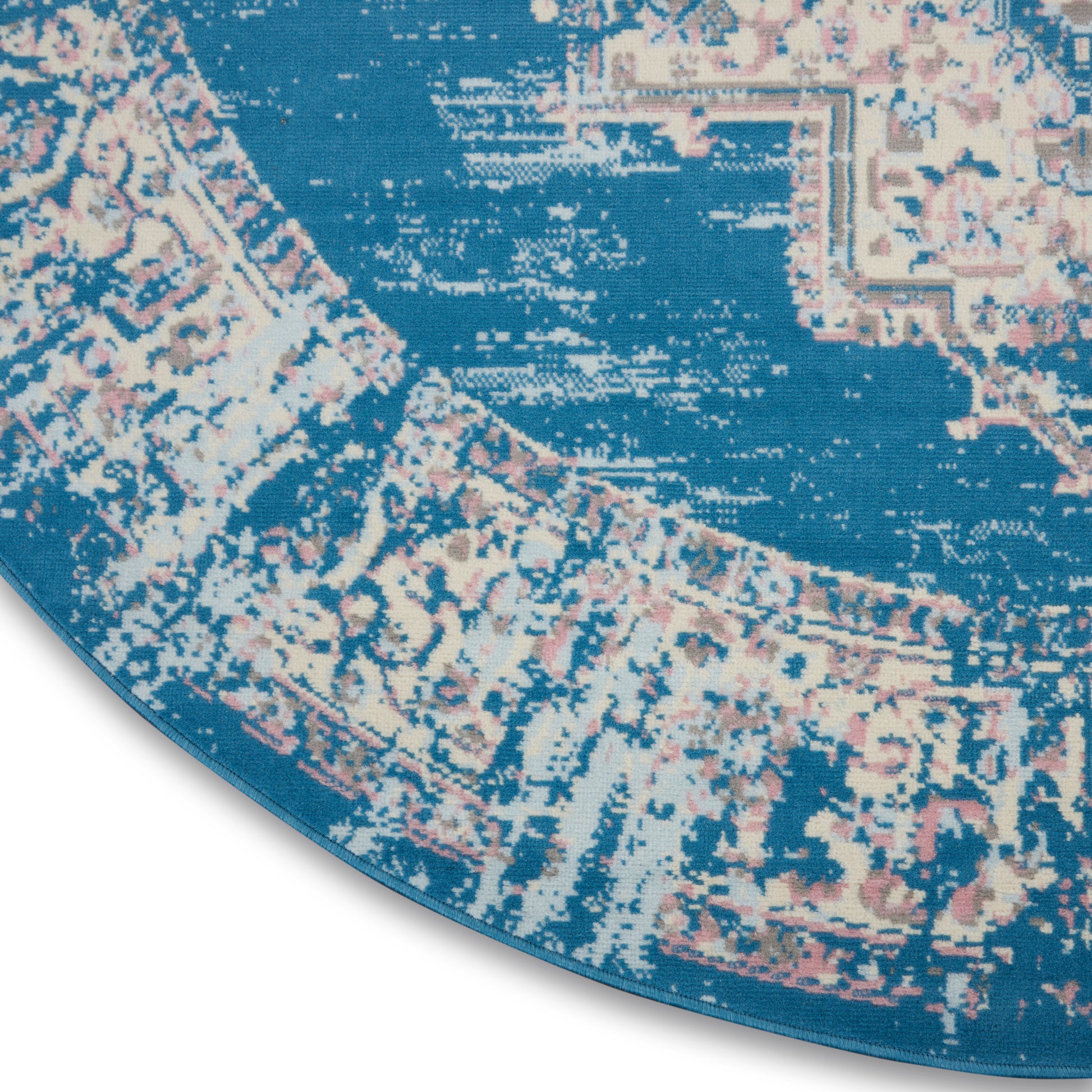 Round blue rug with pink and ivory vintage oriental pattern, woven texture and bound edge.