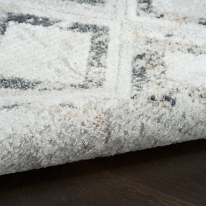 Plush cream rug with gray geometric pattern and rolled edge on dark wood floor.