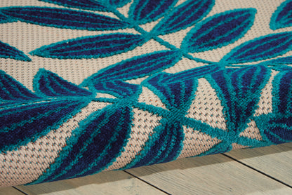 Close-up of a woven rug with blue leaf pattern on cream background and textured fibers on a wooden floor.