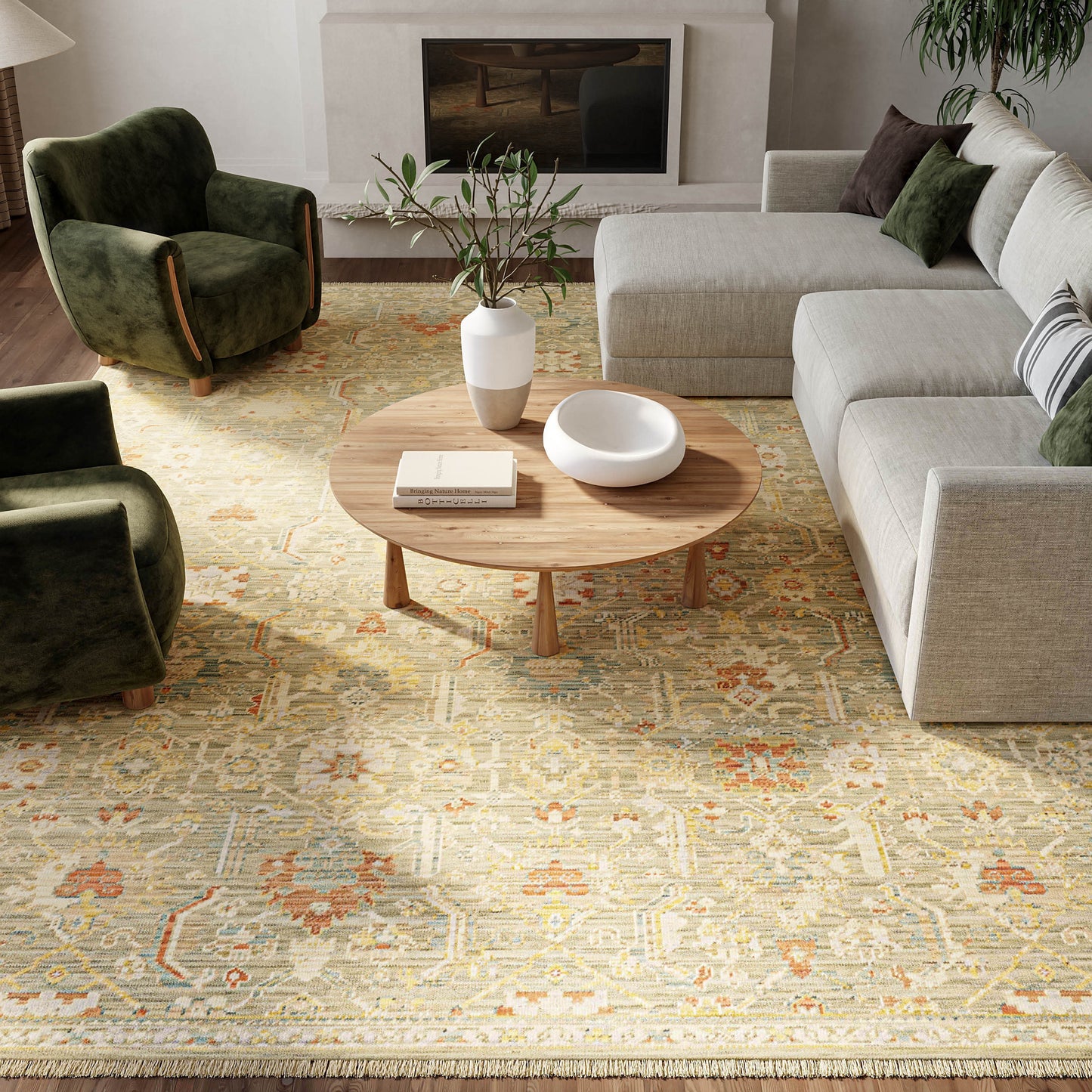 Modern living room with light gray sectional, olive-green velvet chairs, wood coffee table, vase, bowl, and patterned rug.