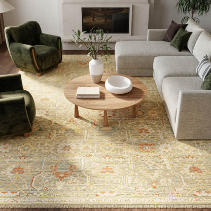 Modern living room with light gray sectional, olive-green velvet chairs, wood coffee table, vase, bowl, and patterned rug.