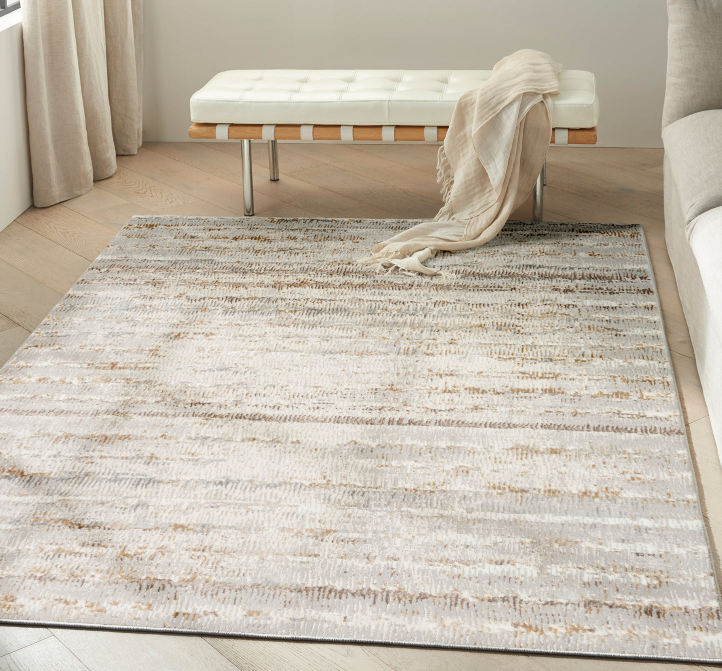Abstract cream, beige and gray area rug in a modern living room with a white tufted bench and beige throw.
