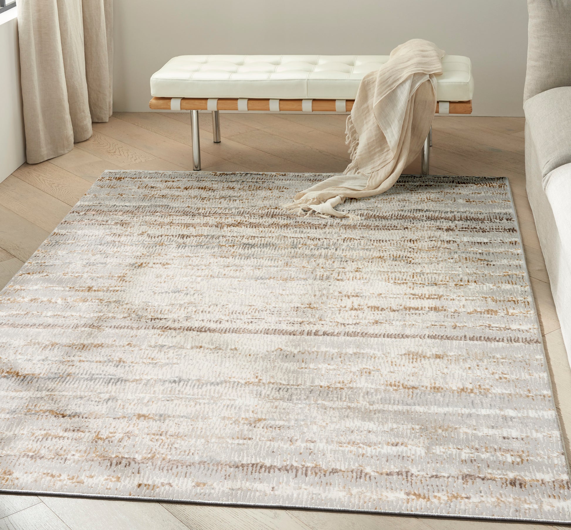 Abstract cream, beige and gray area rug in a modern living room with a white tufted bench and beige throw.